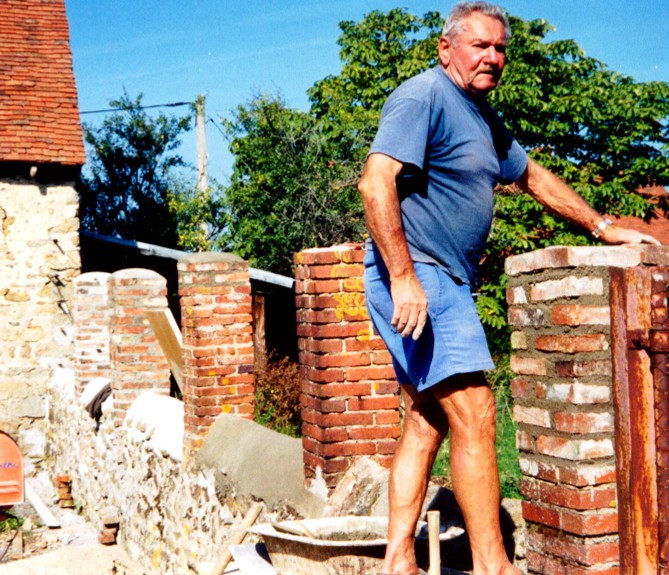 A man standing beside an old brick and stone wall