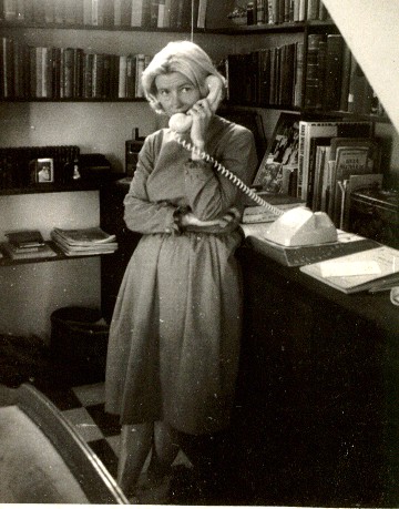 A woman on the telephone in a book-lined study, black and white photograph
