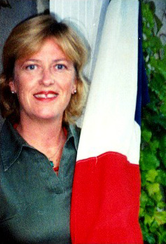 A smiling woman beside a French flag
