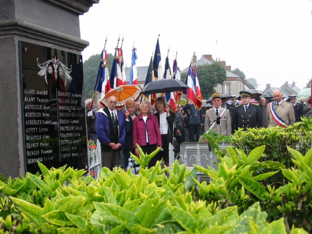Memorial stone with flags and a crowd behind it