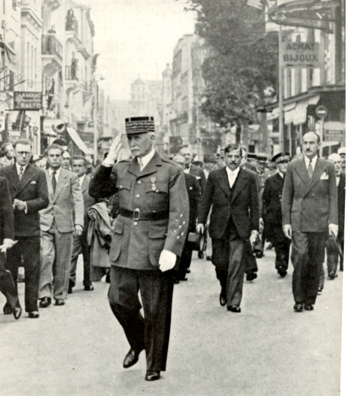 Marshal Pétain leaving the church at Vichy for the Monument aux Morts--July 14, 1940. Pierre Laval (right, black coat), Vichy's prime minister, was...