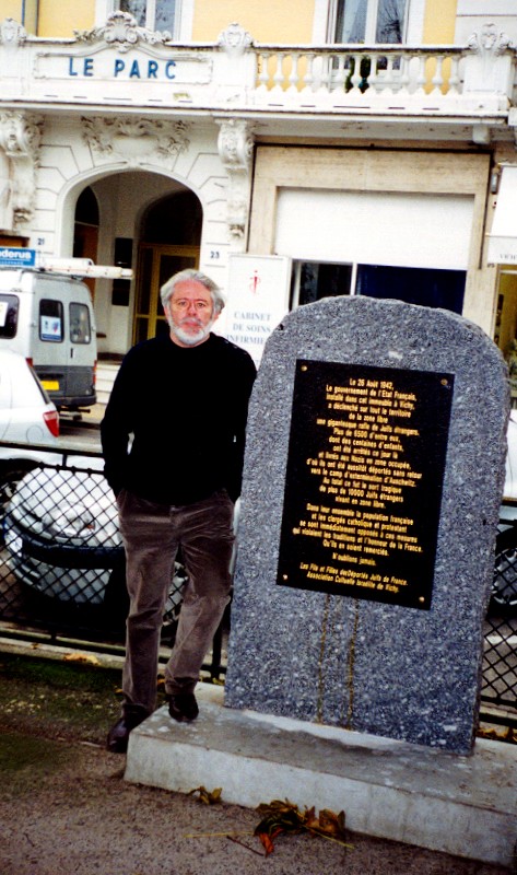 A man standing beside a memorial plaque