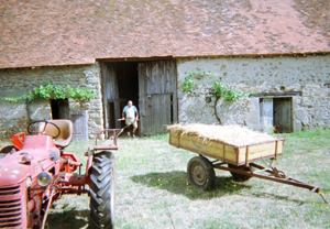 A red tractor and a wooden cart in a farmyard