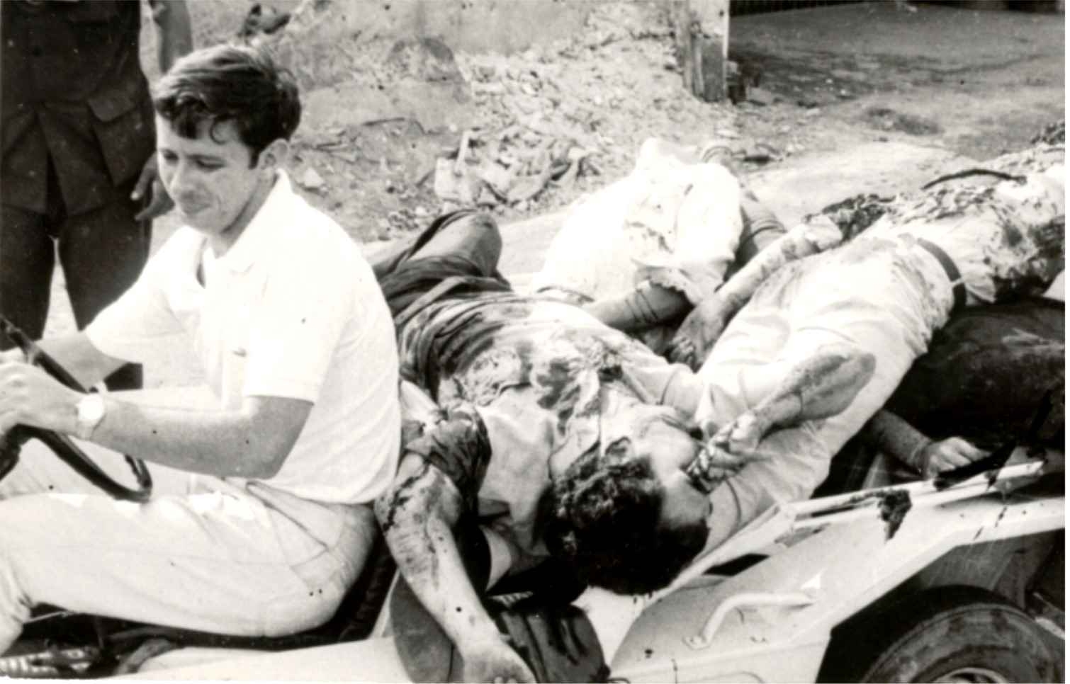 A young man in a jeep beside wounded soldiers, Vietnam