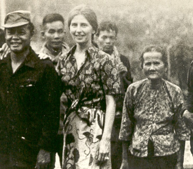 A group of people standing in a forest clearing, black and white photograph