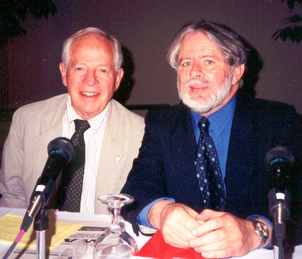 Two men seated at a table with microphones