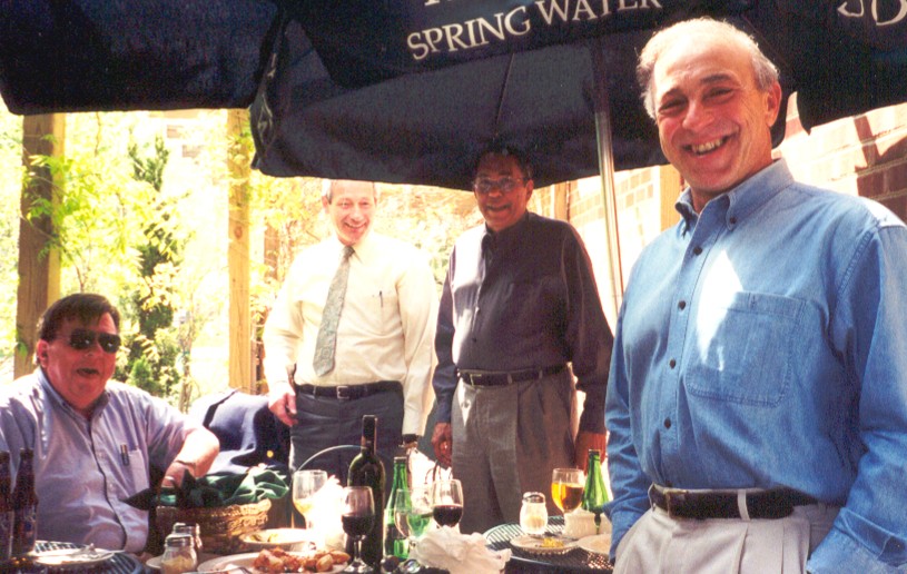 Men at an outdoor table under an umbrella