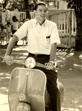 A young man riding a motor scooter