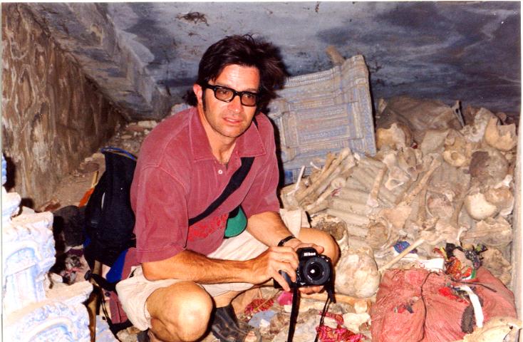 A man with a camera sitting among supplies