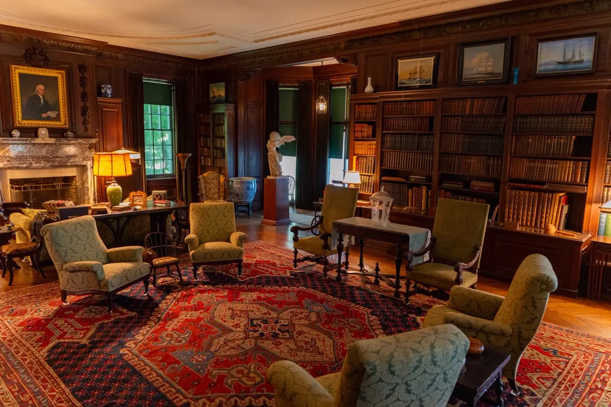 A wood-panelled reading room with armchairs and bookshelves